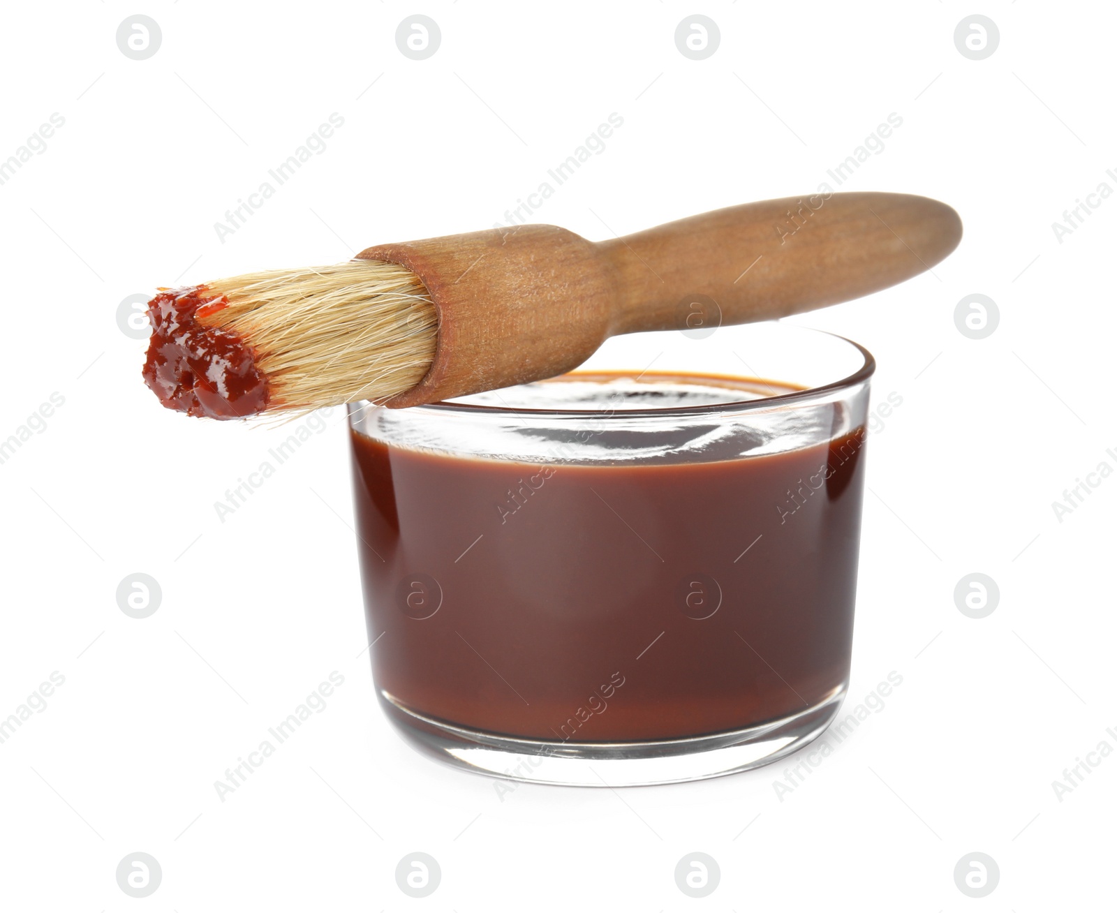 Photo of Glass dish of barbecue sauce with basting brush on white background