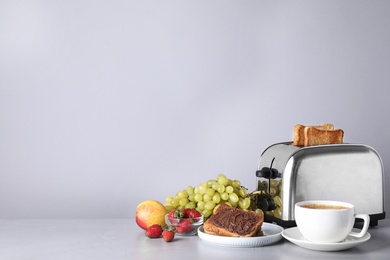 Healthy breakfast and modern toaster on light grey table, space for text