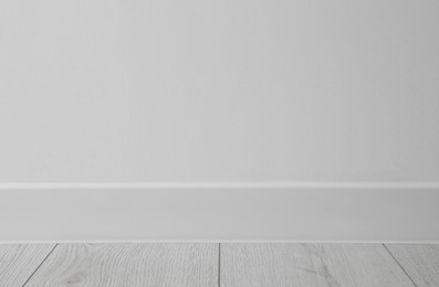 Photo of White plinth on laminated floor near wall indoors