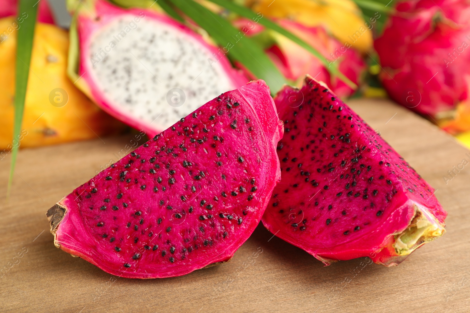 Photo of Delicious cut red pitahaya fruit on wooden board, closeup