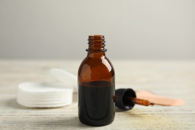 Photo of Bottle of medical iodine and dropper on white wooden table