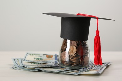 Scholarship concept. Graduation cap, coins and banknotes on white wooden table