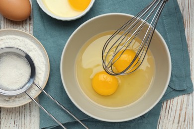Whisking eggs in bowl on wooden table, top view