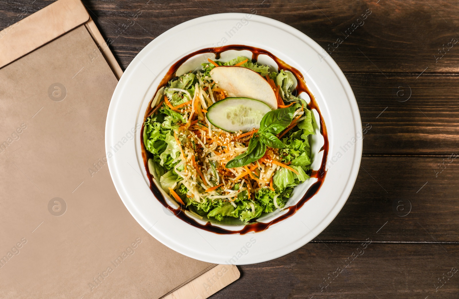 Photo of Plate with delicious fresh salad and menu on table, top view