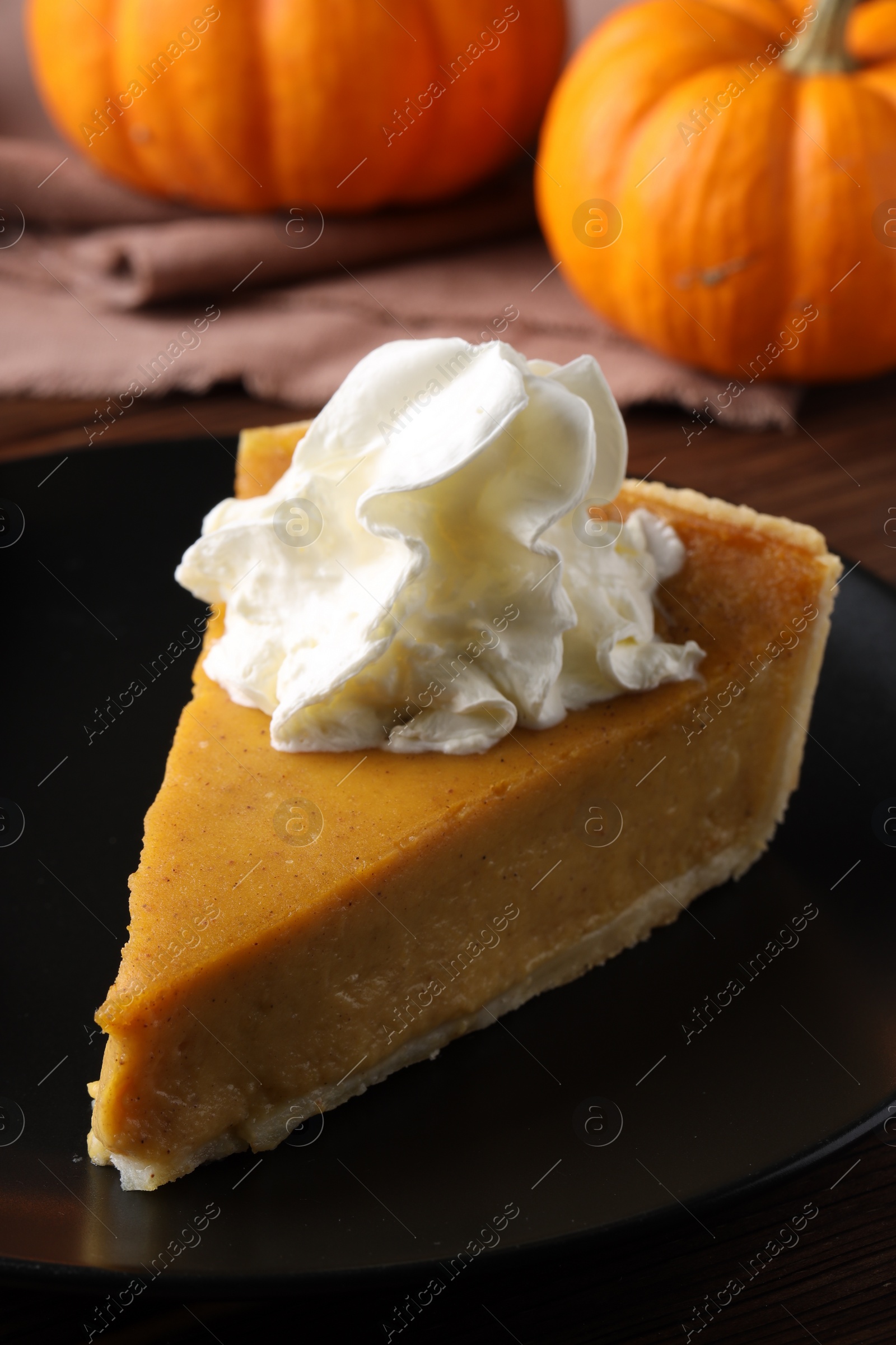 Photo of Piece of delicious pumpkin pie with whipped cream on table, closeup