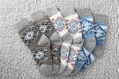 Photo of Knitted socks on grey fur background, flat lay