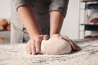 Man kneading dough at table in kitchen, closeup