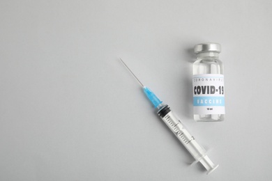 Photo of Vial with coronavirus vaccine and syringe on light background, flat lay. Space for text