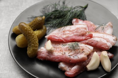 Tasty pork fatback with pickled cucumbers and spices on grey table, closeup