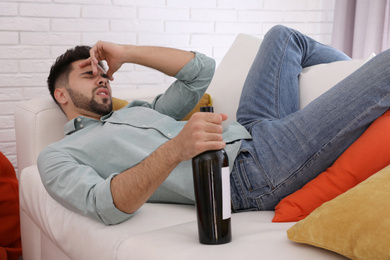 Photo of Young man suffering from hangover in room after party