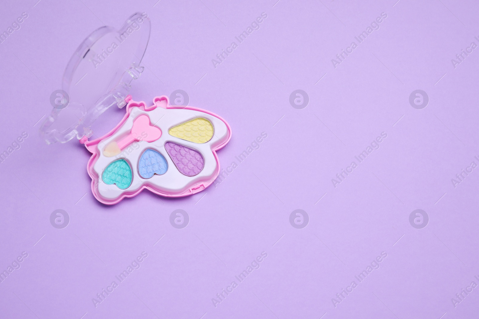 Photo of Children's eye shadow palette with brush on violet background, top view. Space for text