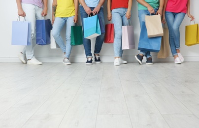 Photo of Group of young people with shopping bags near light wall
