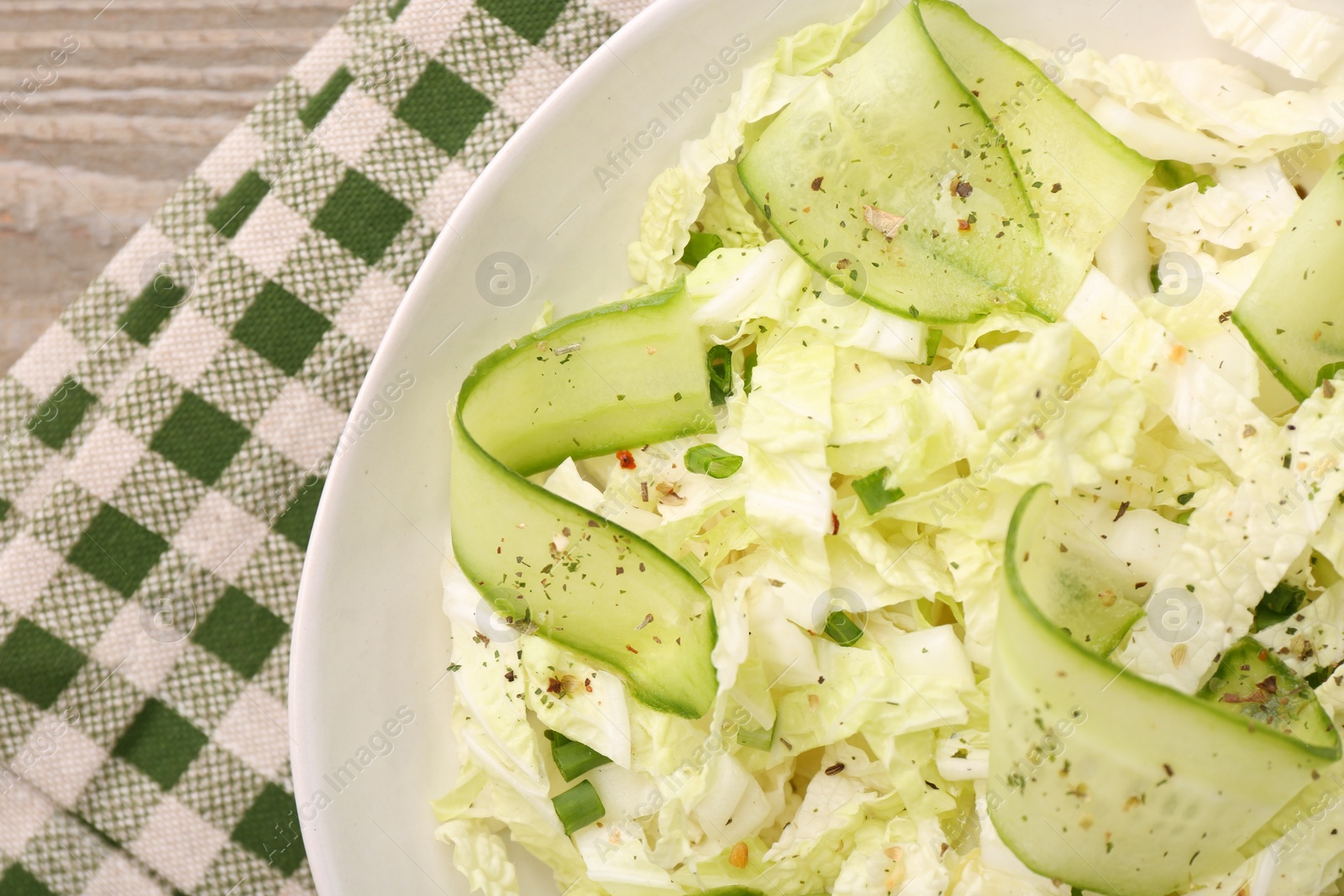 Photo of Tasty salad with Chinese cabbage, cucumber and green onion in bowl on wooden table, top view