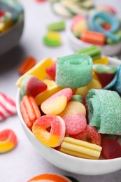 Photo of Bowl of tasty colorful jelly candies on white table, closeup