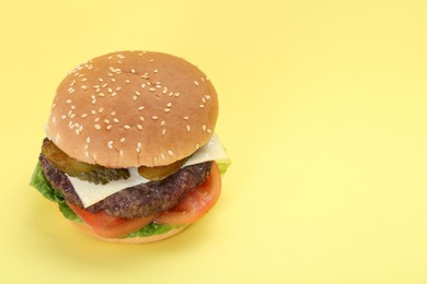 Photo of Burger with delicious patty on yellow background. Space for text