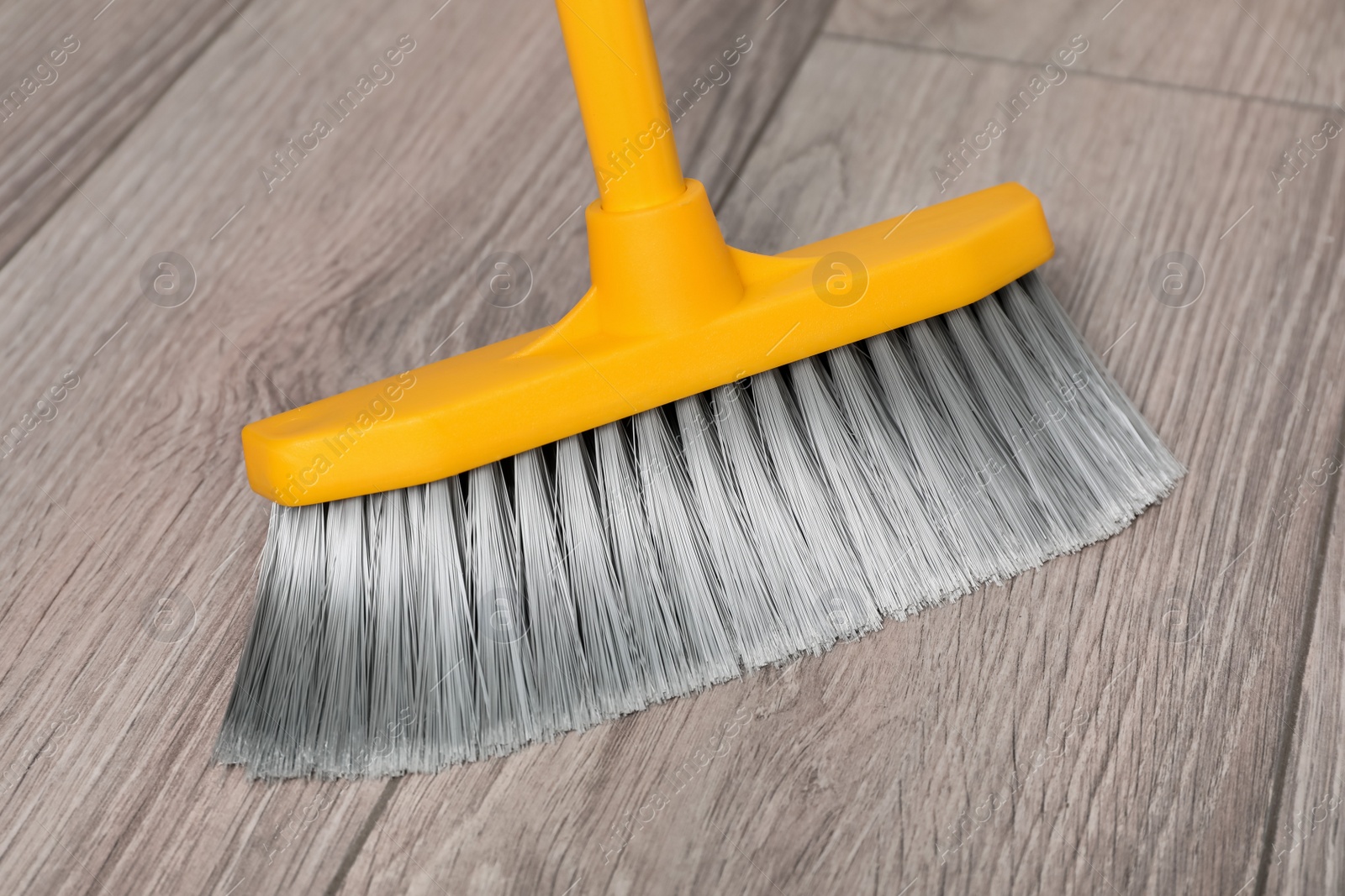 Photo of Sweeping wooden floor with plastic broom, closeup