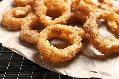 Cooling rack with homemade crunchy fried onion rings, closeup