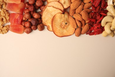 Mix of delicious dried nuts and fruits on beige background, flat lay. Space for text