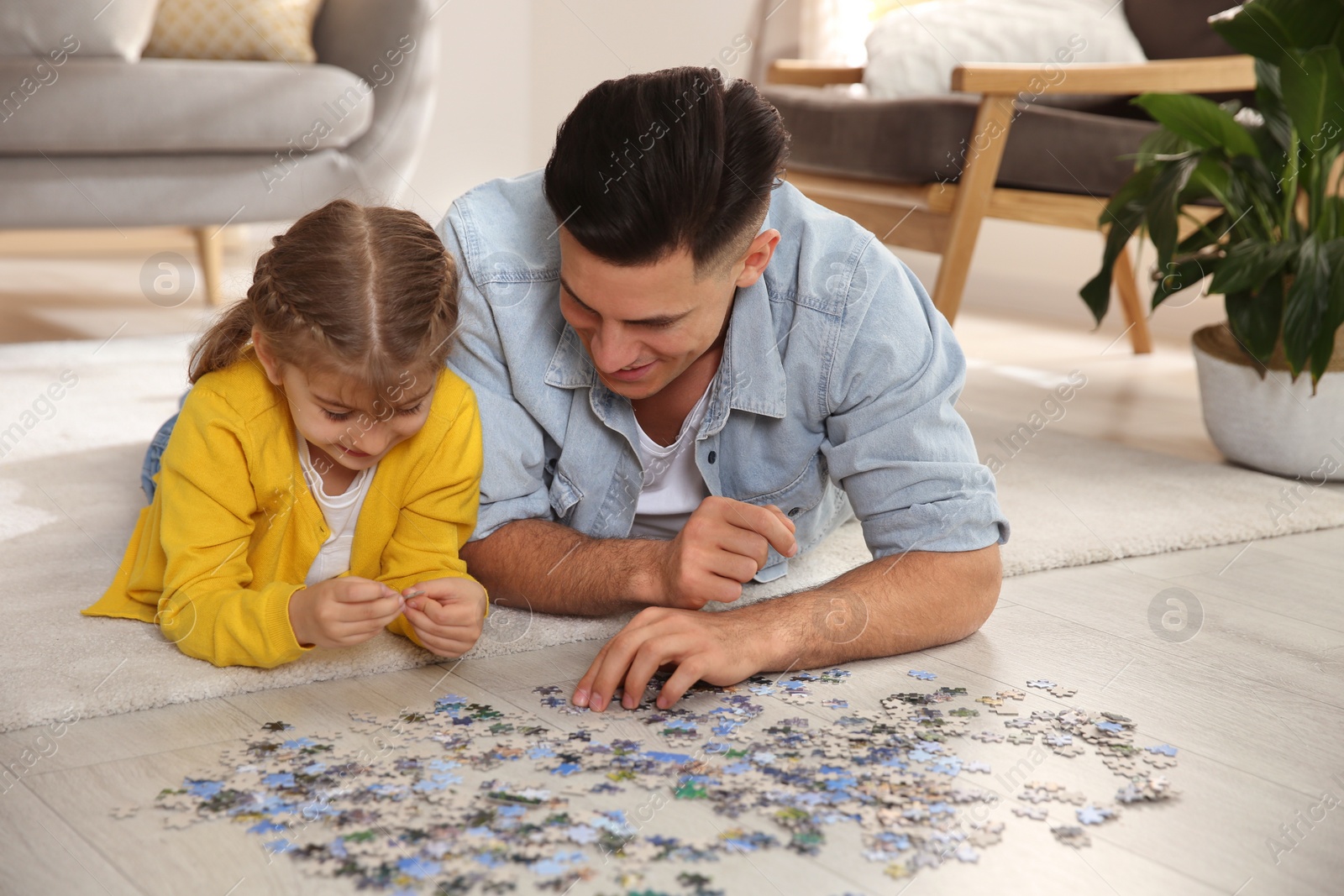 Photo of Happy father and his daughter playing with puzzles on floor at home