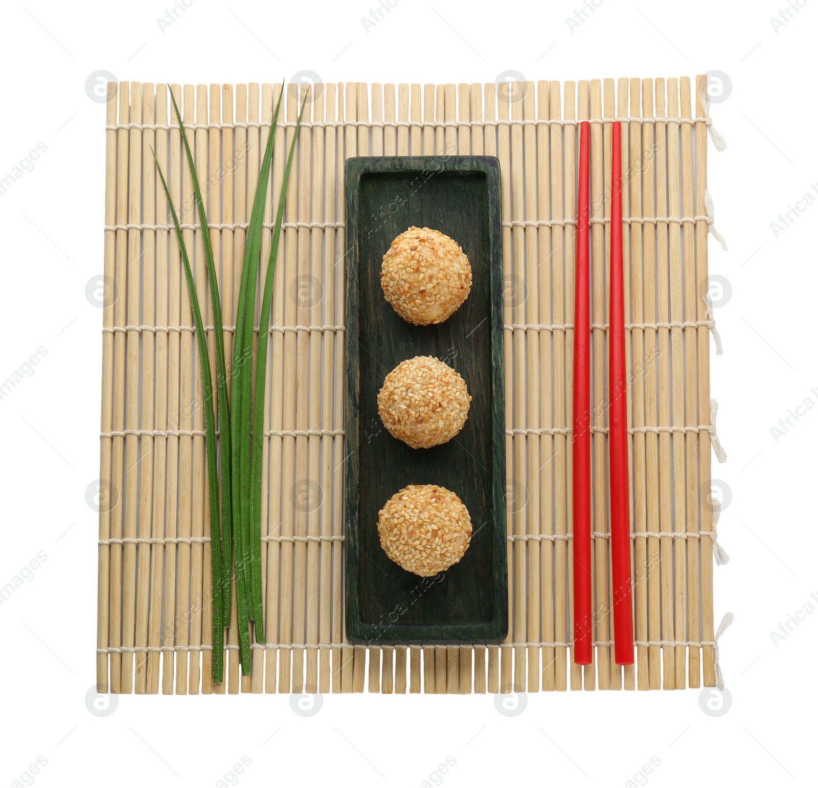 Photo of Delicious sesame balls, green leaves and chopsticks on white background, top view