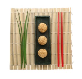 Photo of Delicious sesame balls, green leaves and chopsticks on white background, top view