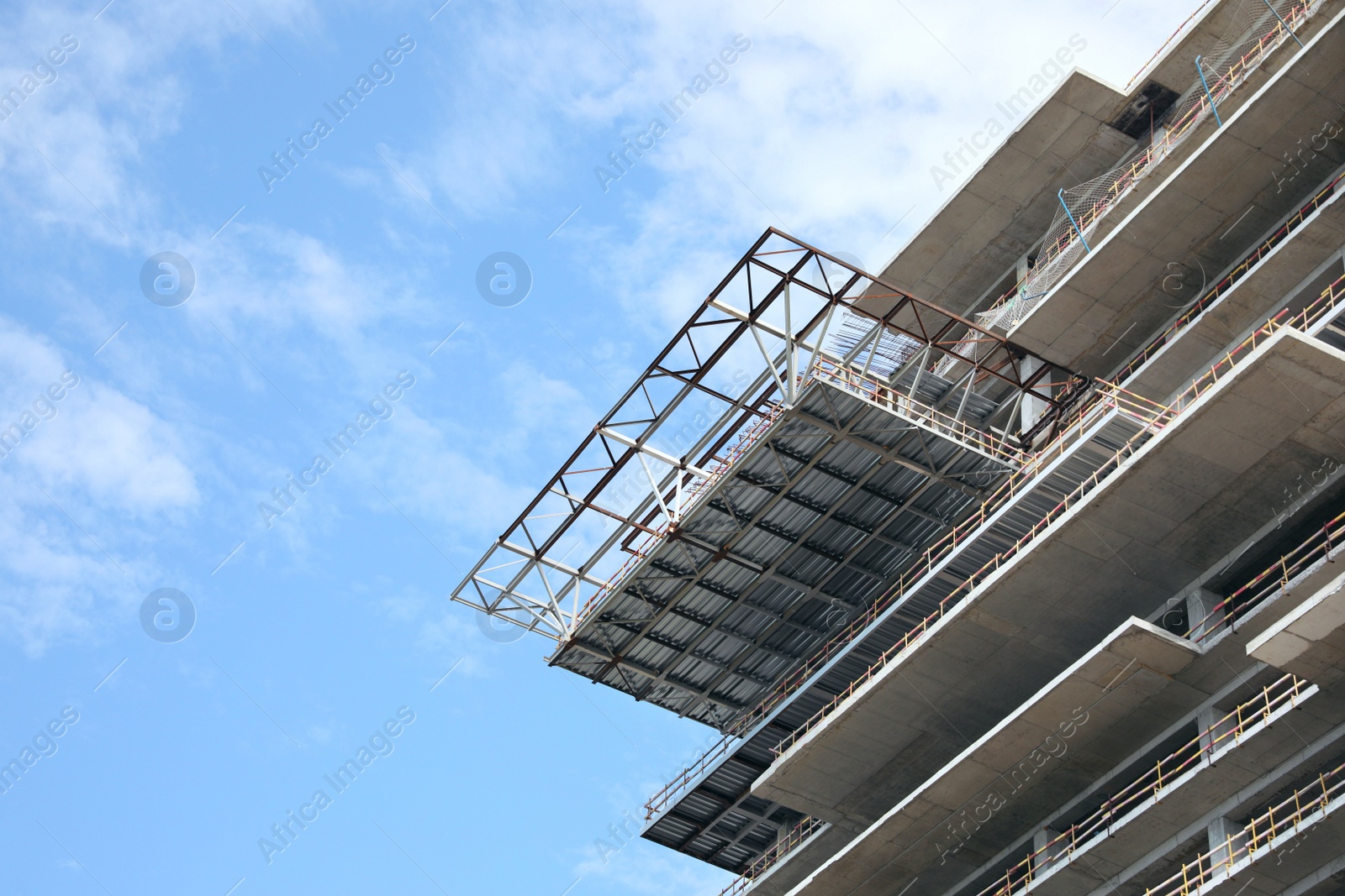 Photo of Multistory building under construction against cloudy sky, low angle view