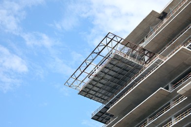 Multistory building under construction against cloudy sky, low angle view