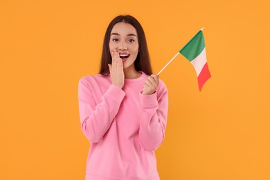 Young woman holding flag of Italy on orange background