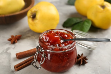Photo of Delicious quince jam and spices on light grey table, closeup