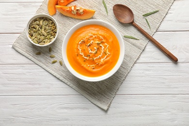 Flat lay composition with bowl of pumpkin soup on wooden table