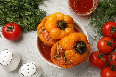 Photo of Tasty stuffed peppers in bowl, spices and products on light grey table, flat lay