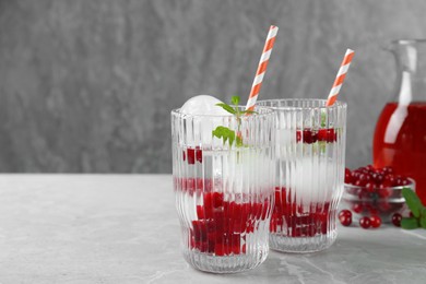 Photo of Delicious cocktails with cranberries, mint and ice balls on grey table, space for text