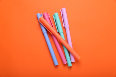 Photo of Many colorful markers on orange background, flat lay