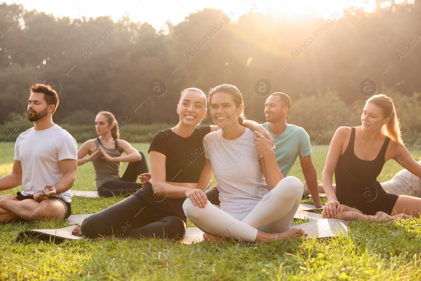 Photo of Women spending time together while practicing yoga on mats outdoors