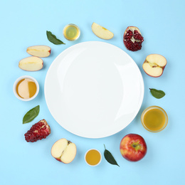 Photo of Flat lay composition with honey and empty plate on light blue background. Rosh Hashanah holiday