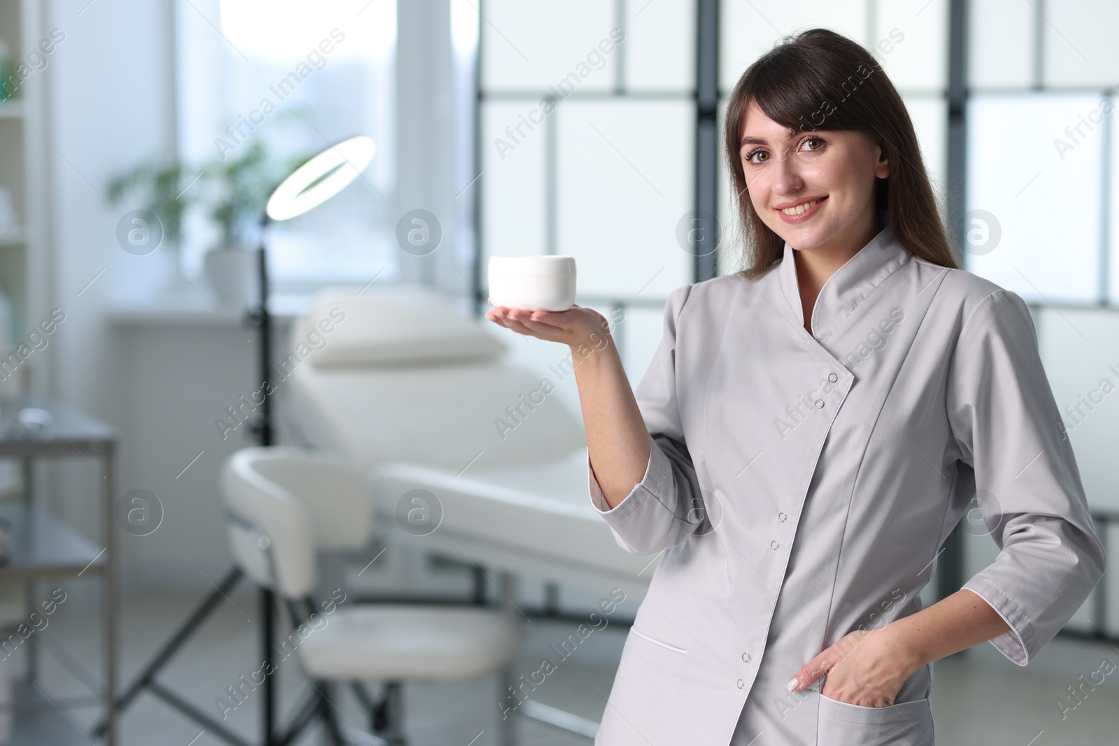 Photo of Cosmetologist with cosmetic product in clinic, space for text