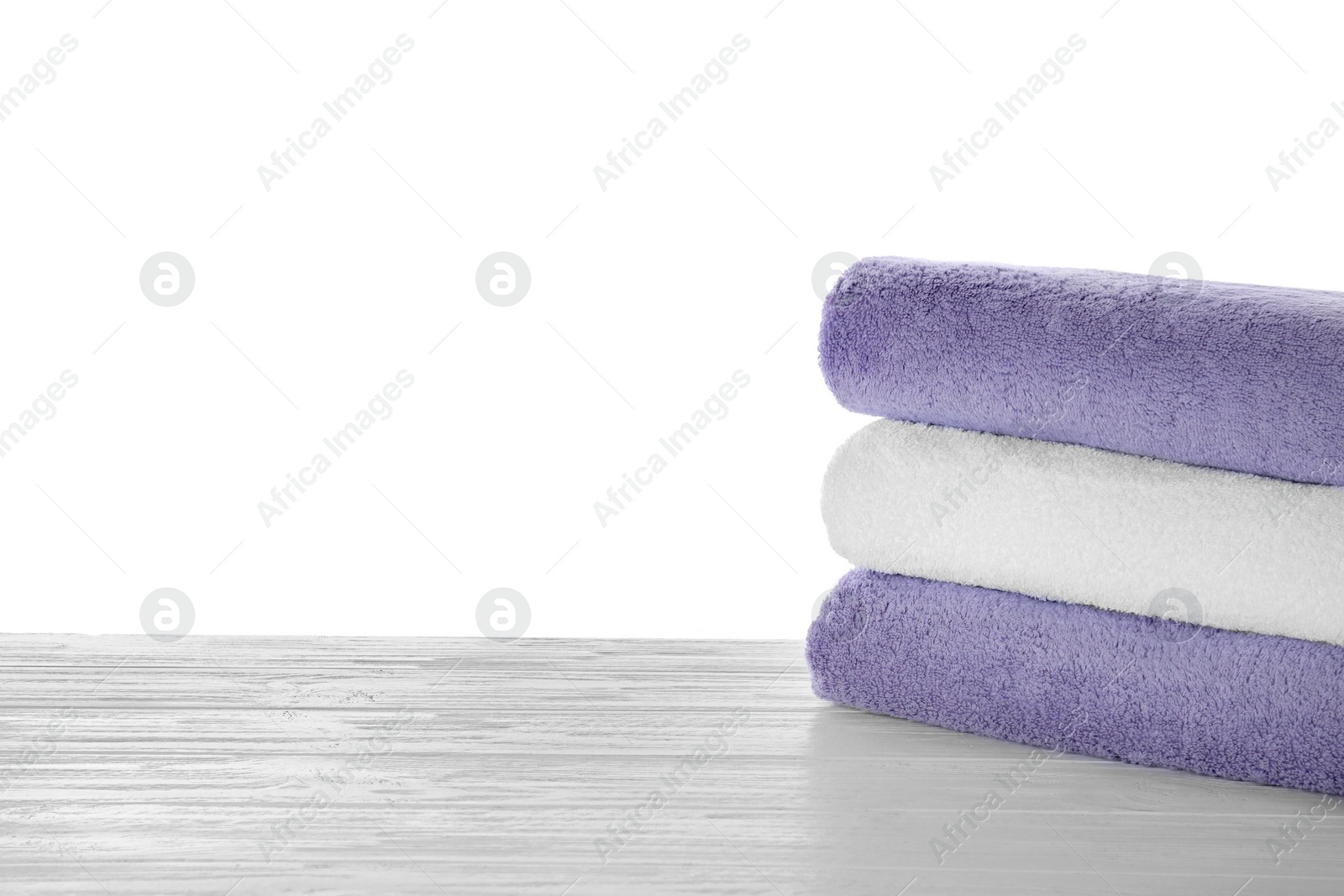 Photo of Fresh towels on wooden table against white background. Space for text