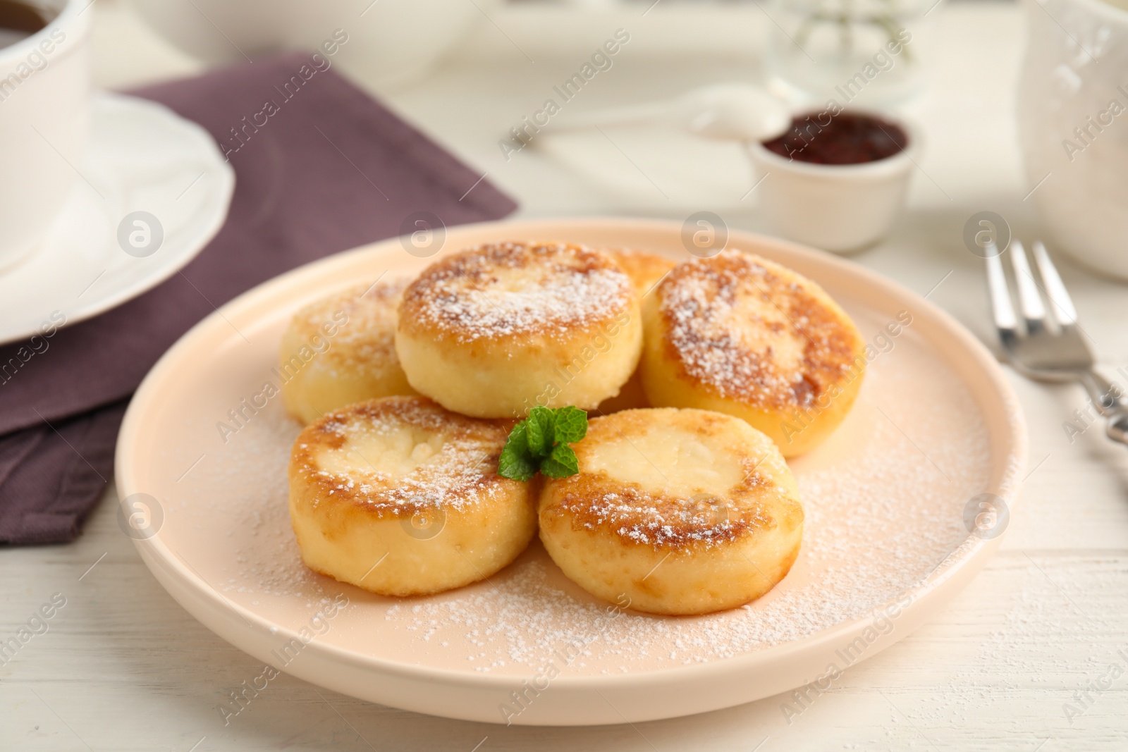 Photo of Delicious cottage cheese pancakes with mint and icing sugar on white wooden table