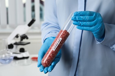 Photo of Scientist holding test tube with minced cultured meat in laboratory, closeup