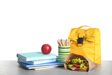 Healthy food, bag and stationery on table against white background. School lunch