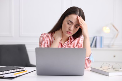 Photo of Young woman suffering from headache at workplace in office