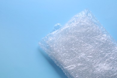 Photo of Folded transparent bubble wrap on light blue background, top view. Space for text