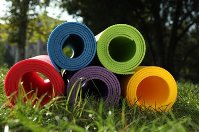 Photo of Bright exercise mats on fresh green grass outdoors