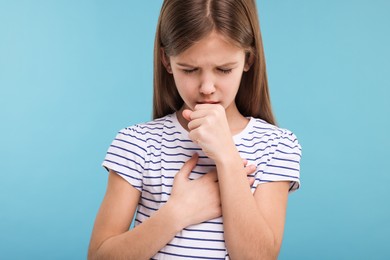 Photo of Sick girl coughing on light blue background