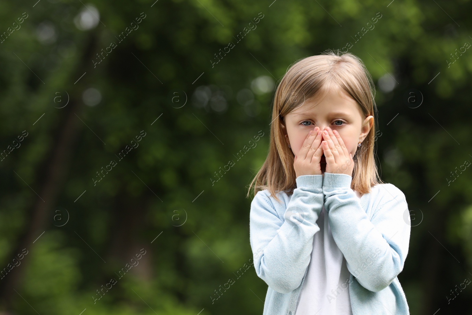 Photo of Little girl suffering from seasonal spring allergy outdoors, space for text