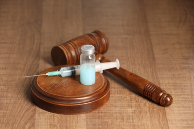 Photo of Law concept. Gavel, syringe and glass vial on wooden table