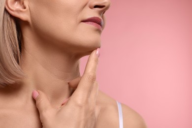 Photo of Woman touching her neck on pink background, closeup