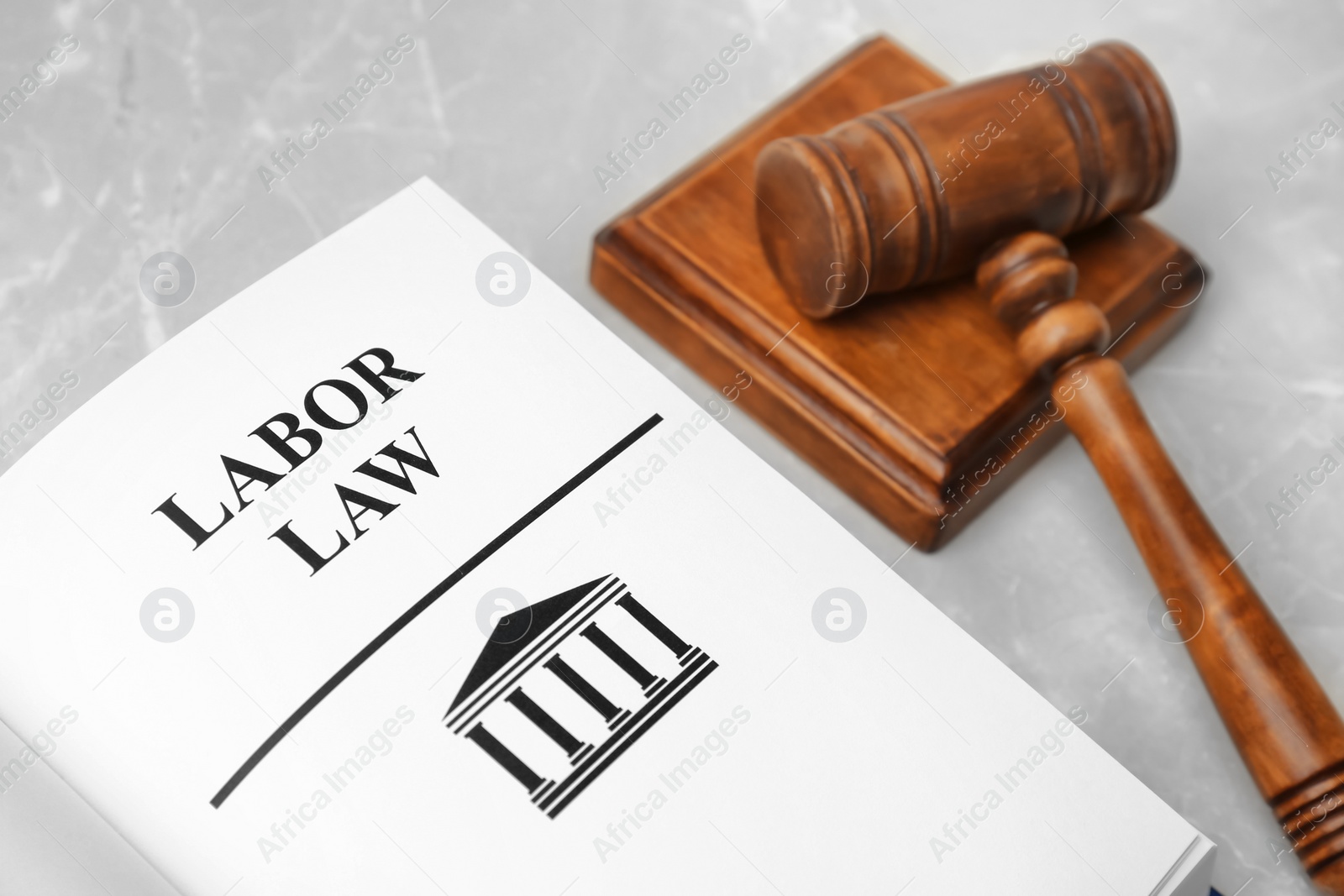 Photo of Open book with words LABOR LAW and gavel on table, closeup