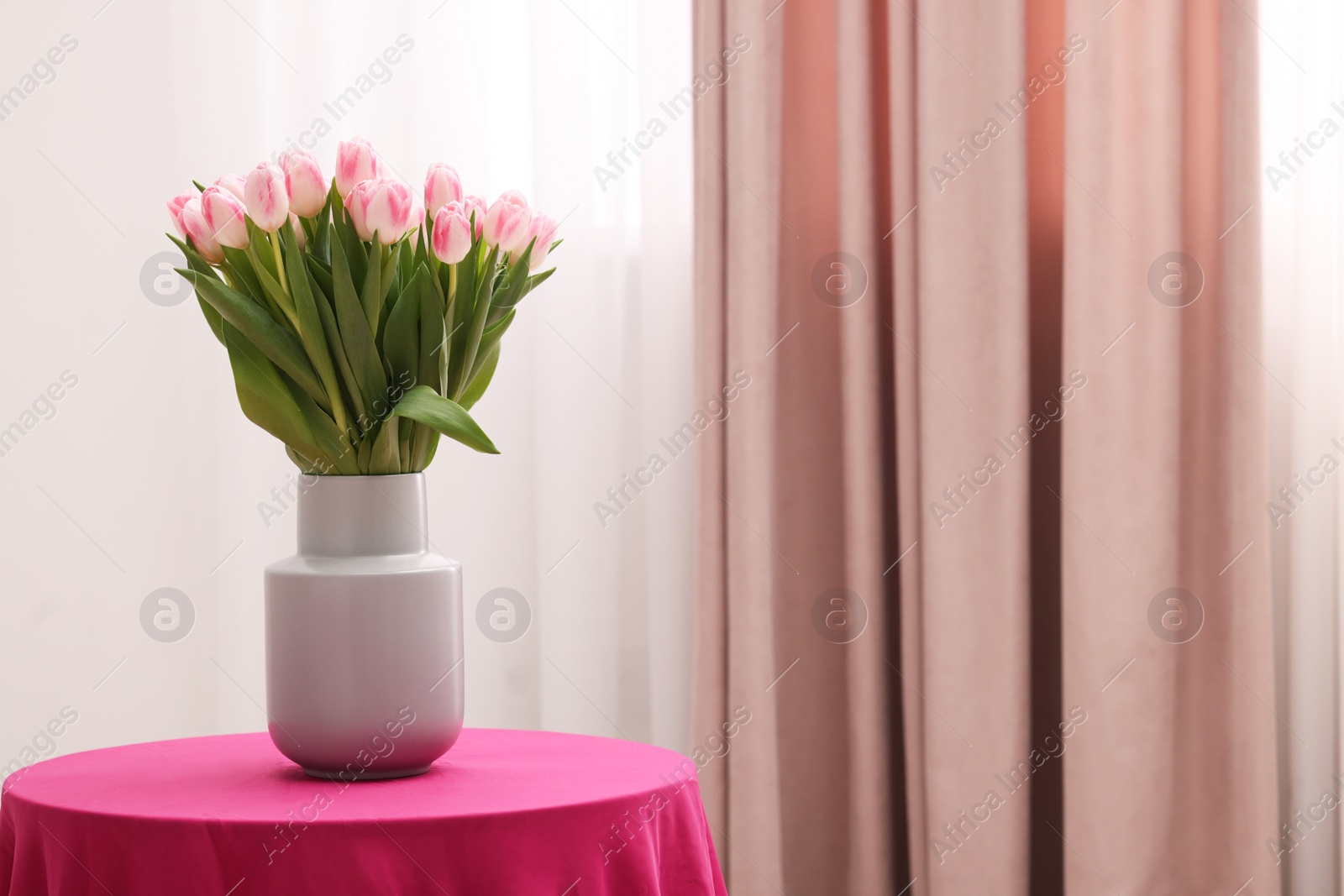 Photo of Beautiful bouquet of fresh pink tulips on table indoors. Space for text