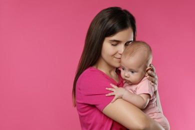 Beautiful mother with her cute baby on pink background. Space for text